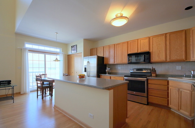 1283 Georgetown Way Vernon Hills, IL 60061 - Photo 7 of 25 a kitchen with stainless steel appliances a stove a sink a microwave a refrigerator a dining table and chairs with wooden floor