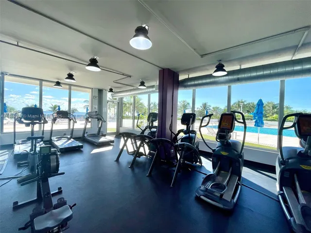 a living room with furniture gym equipment and large windows