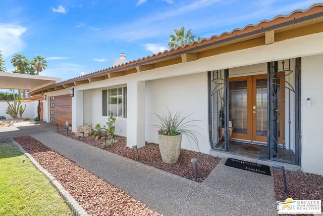 a front view of a house with a yard and potted plants