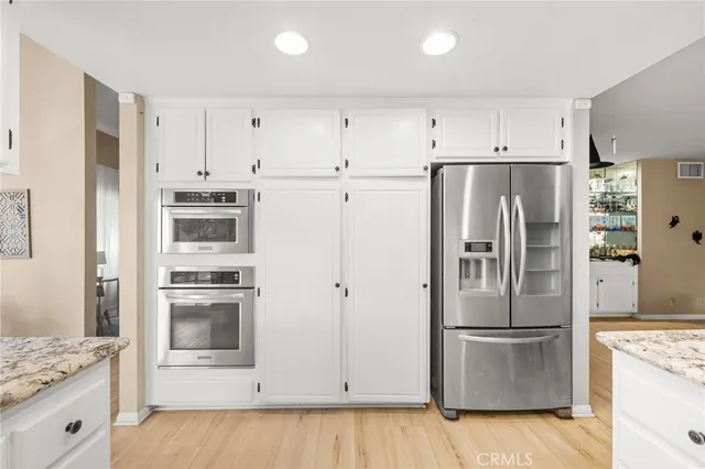 a kitchen with stainless steel appliances a refrigerator stove and white cabinets