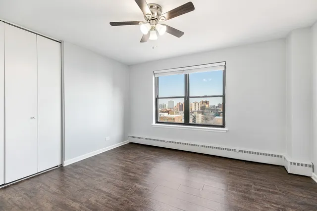 an empty room with wooden floor chandelier fan and windows