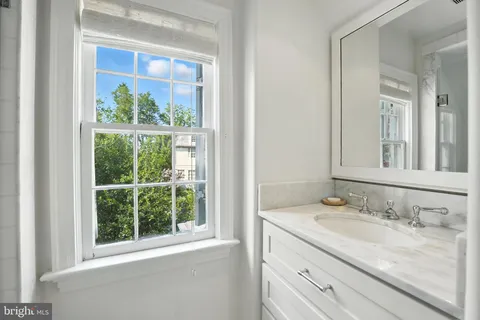 a bathroom with a granite countertop sink a large mirror and a window
