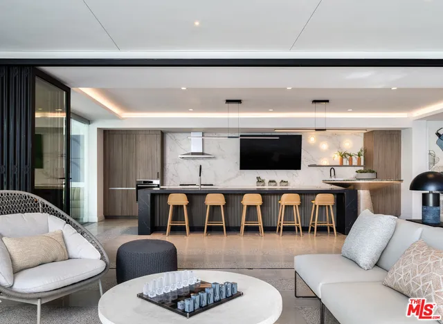 a living room with furniture kitchen view and a large window