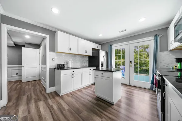 a kitchen with white cabinets and wooden floor