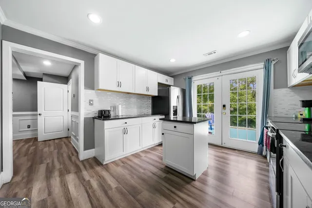 a kitchen with white cabinets and wooden floor