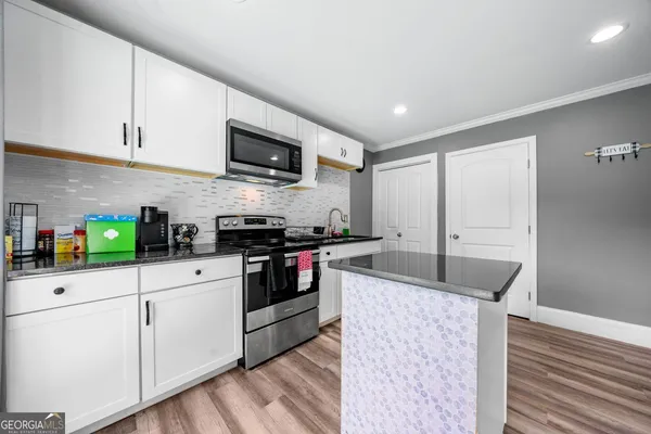 a kitchen with granite countertop a sink stainless steel appliances and white cabinets