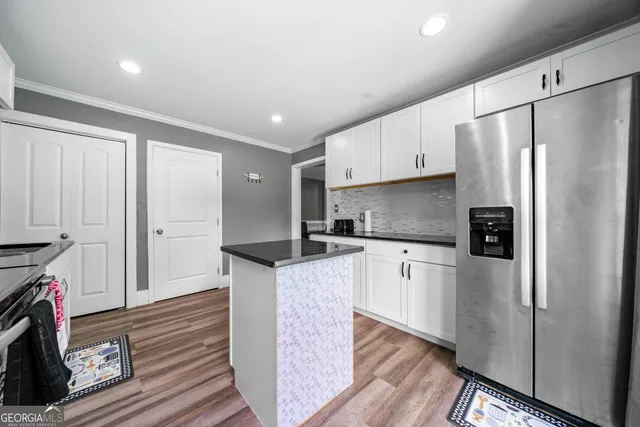 a kitchen with granite countertop a refrigerator stove and wooden floor