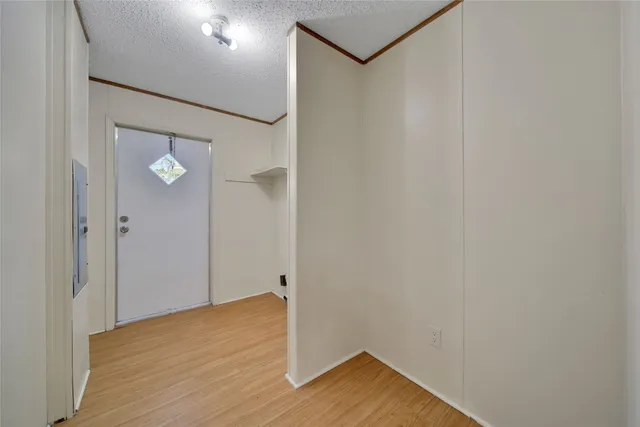 a view of an empty room with wooden floor and a ceiling fan