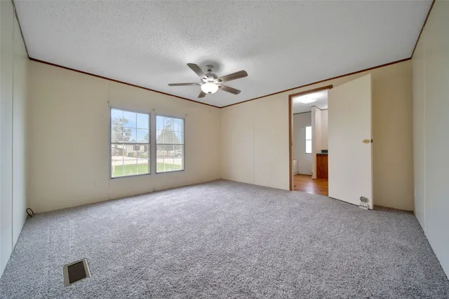 an empty room with windows and ceiling fan