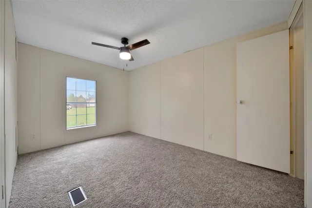 an empty room with windows and fan