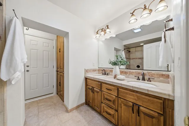 a view of a white house with a small yard plants and large tree