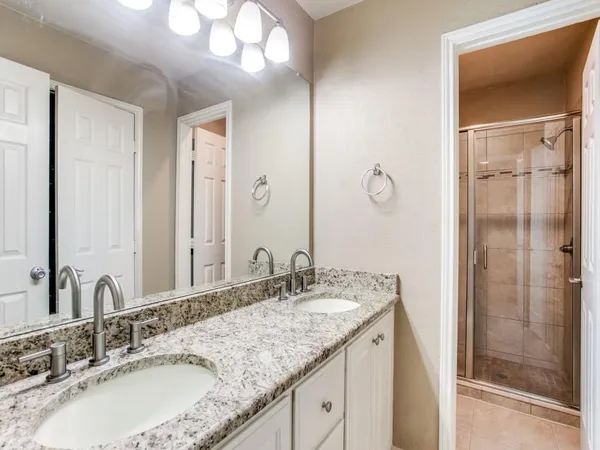 a bathroom with a granite countertop sink a mirror and shower