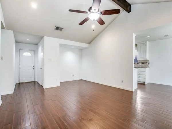 an empty room with wooden floor ceiling fan and windows