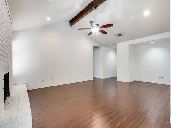 an empty room with wooden floor fan and windows