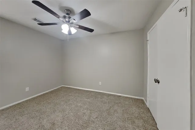 a view of an empty room with a chandelier fan