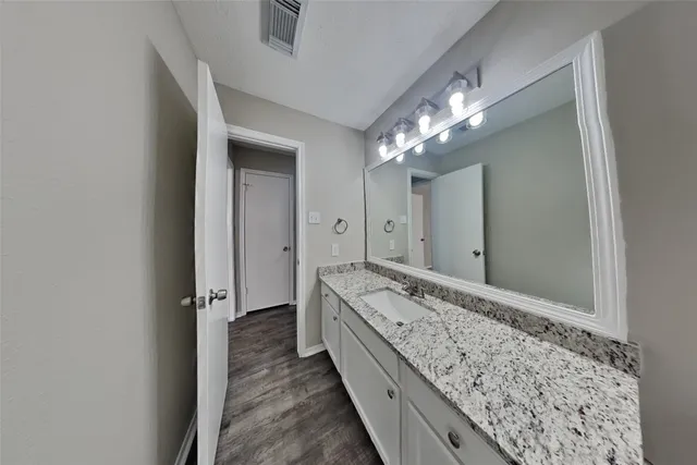 a bathroom with a granite countertop sink a mirror and shower