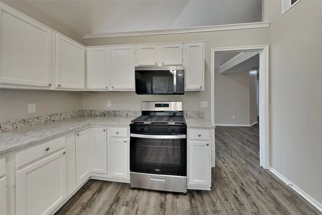 a kitchen with granite countertop white cabinets and white appliances