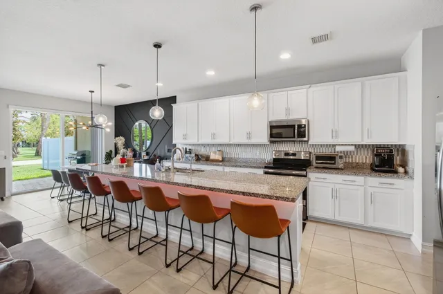 a kitchen with stainless steel appliances kitchen island granite countertop a stove a sink a dining table and chairs with wooden floor