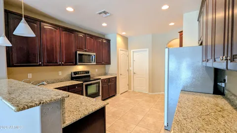 a large kitchen with stainless steel appliances granite countertop a refrigerator and a stove top oven