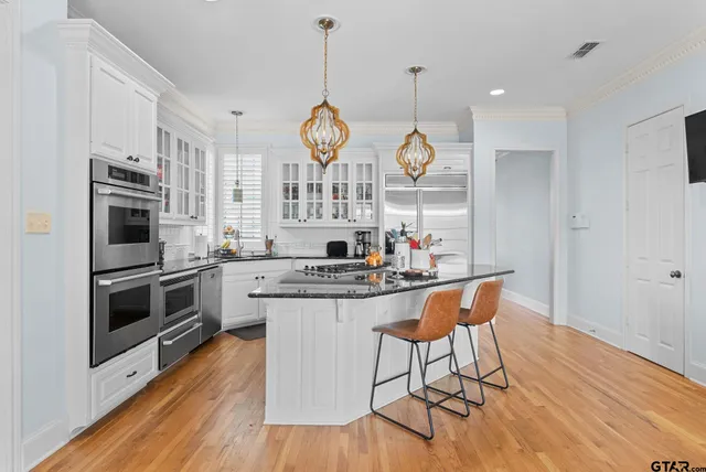 a kitchen with stainless steel appliances a large stove a sink dishwasher a microwave oven with cabinets and wooden floor