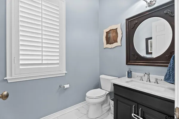 a bathroom with a toilet a sink a mirror and a window