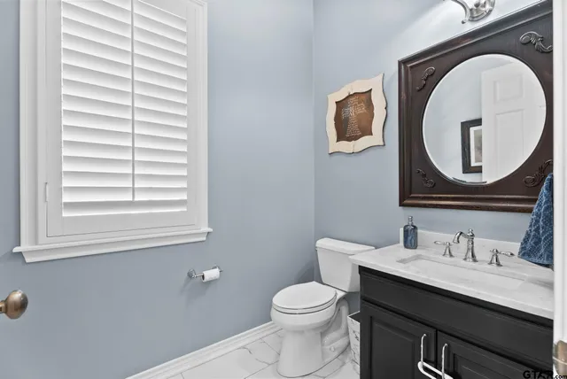 a bathroom with a toilet a sink a mirror and a window