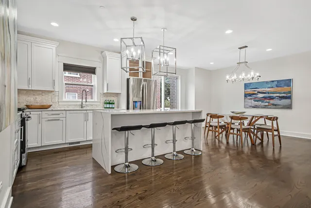 a kitchen with a refrigerator a sink dishwasher a dining table and chairs with wooden floor