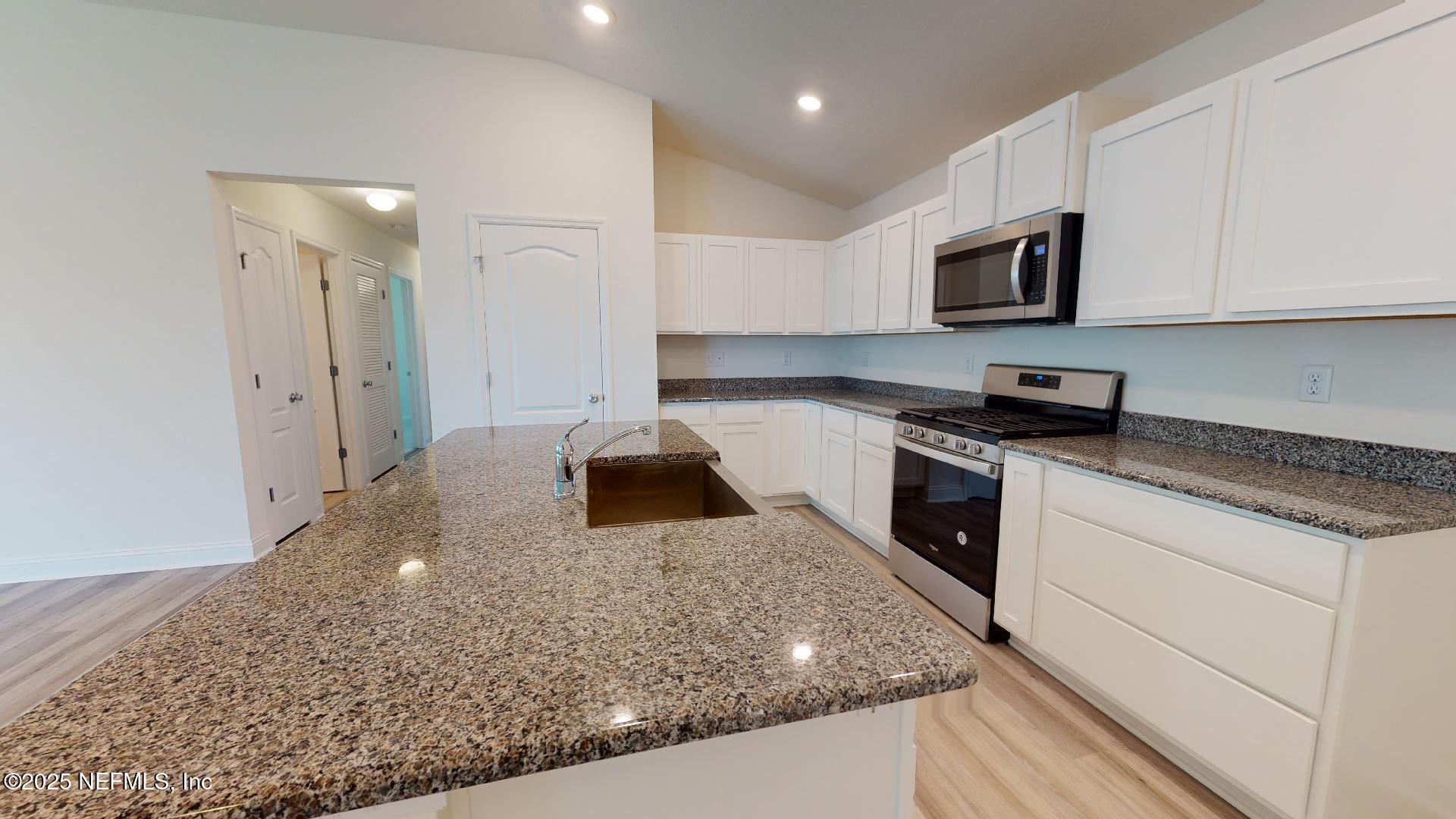 408 Bluejack Lane St. Augustine, FL 32095 - Photo 7 of 30 a kitchen with stainless steel appliances granite countertop a sink stove and microwave