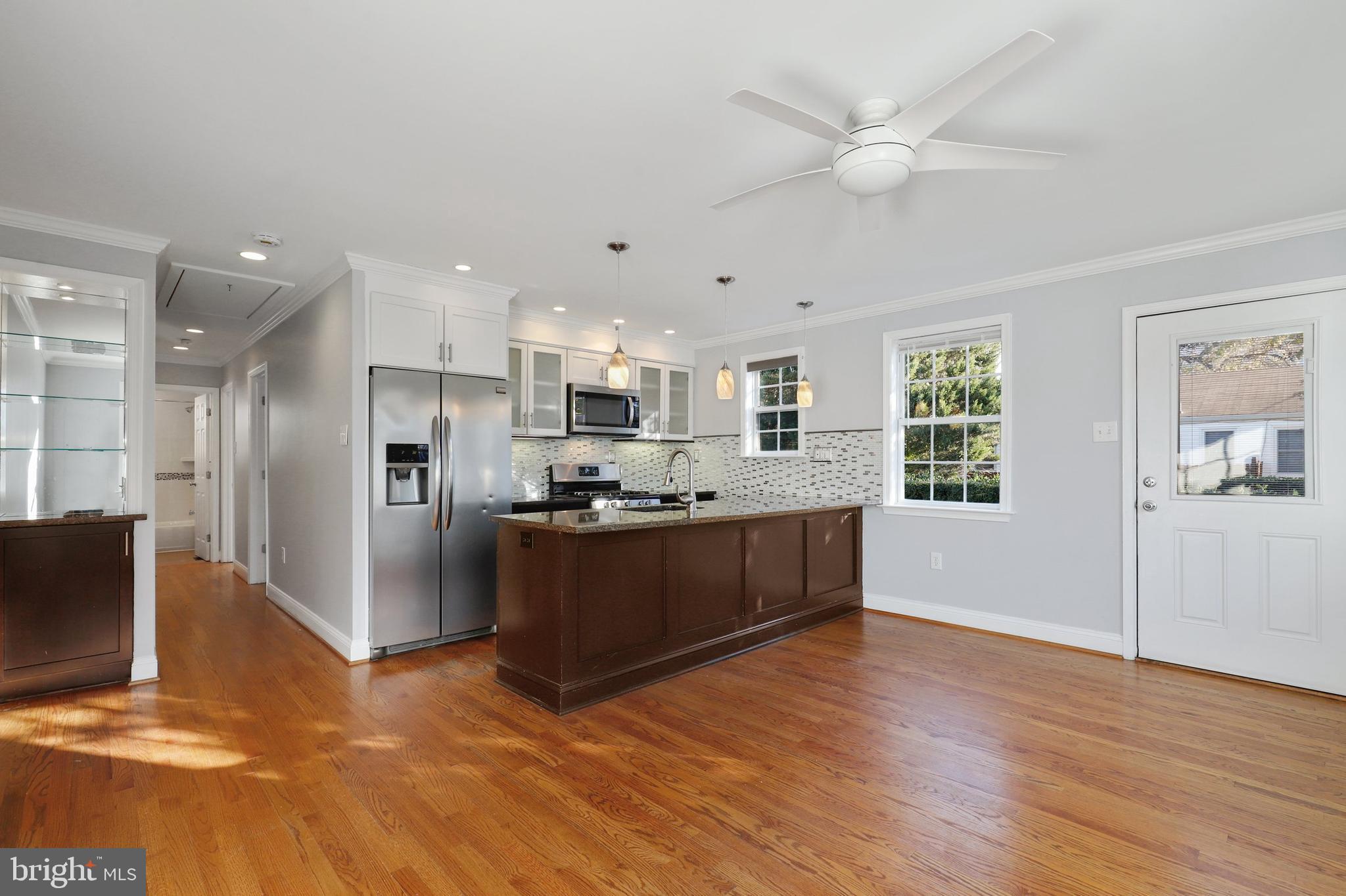 a large kitchen with stainless steel appliances kitchen island granite countertop a refrigerator a sink a stove a dining table and chairs with wooden floor