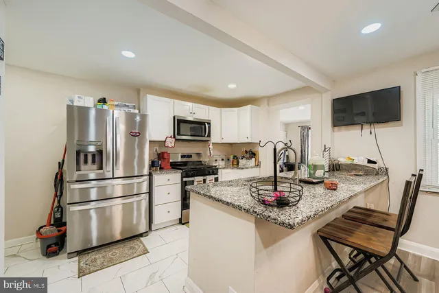 a kitchen with granite countertop a refrigerator stove top oven and sink