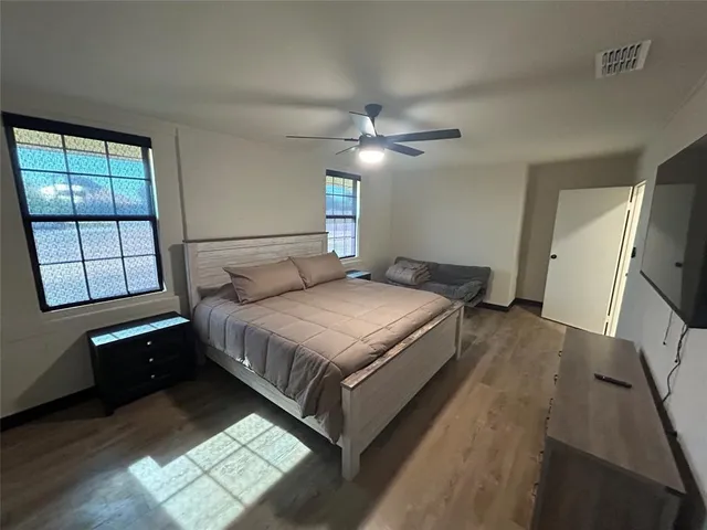 a bedroom with a bed next to a window with a flat screen tv