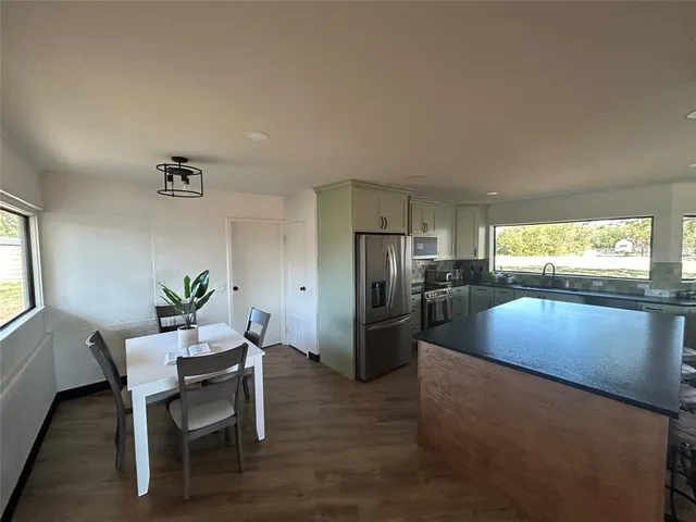 a kitchen with stainless steel appliances wooden floor and dining table