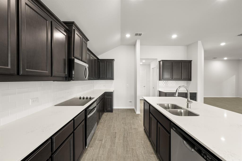 2607 Streamside Drive Burleson, TX 76028 - Photo 6 of 27 a kitchen with stainless steel appliances granite countertop a sink a stove top oven and wooden floor