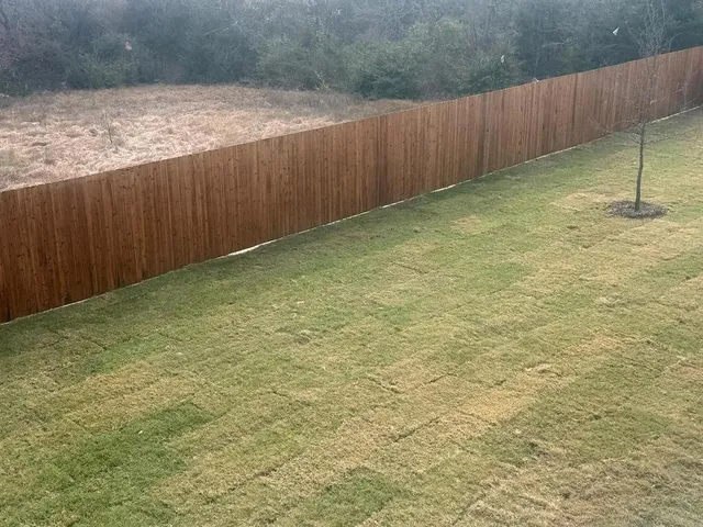 a view of a yard with wooden fence