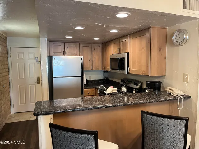 a kitchen with kitchen island granite countertop a sink a stove a refrigerator a washer and dryer