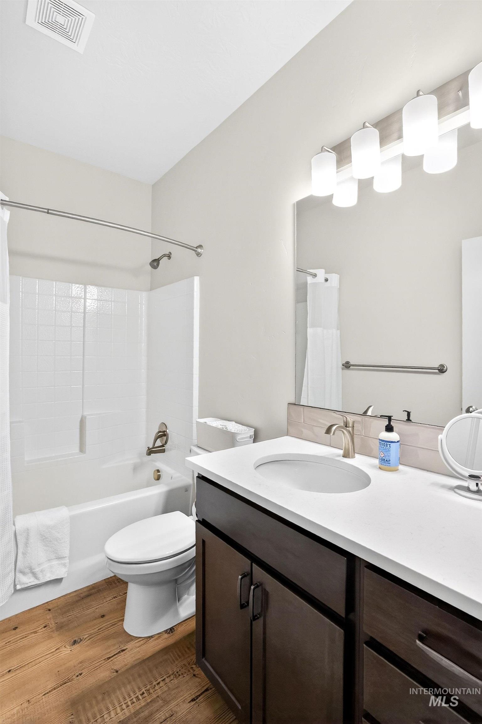 311 Broken Ridge Way McCall, ID 83638 - Photo 22 of 44 Bathroom featuring a white bathtub with subway tile surround, dark wood-finish vanity with white countertop, and wood-finish flooring
