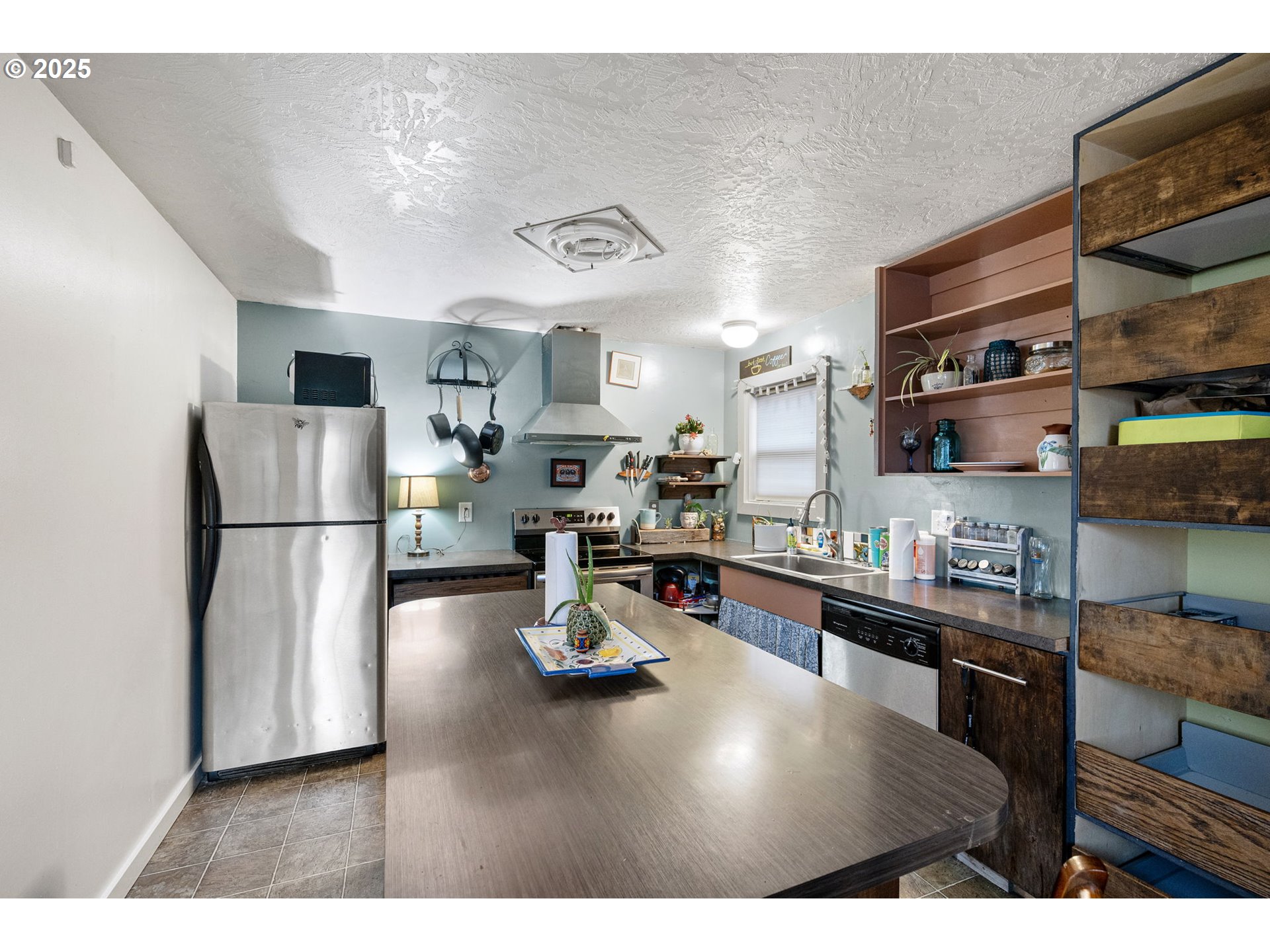1425 East Madison Avenue Cottage Grove, OR 97424 - Photo 11 of 39 a kitchen with stainless steel appliances granite countertop a refrigerator a sink dishwasher a stove a dining table and chairs with wooden floor
