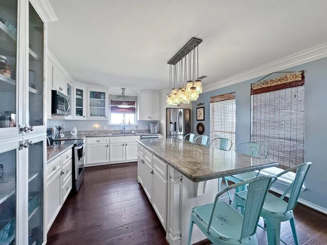 a kitchen with stainless steel appliances granite countertop a kitchen island a stove a sink dishwasher a dining table and chairs with wooden floor