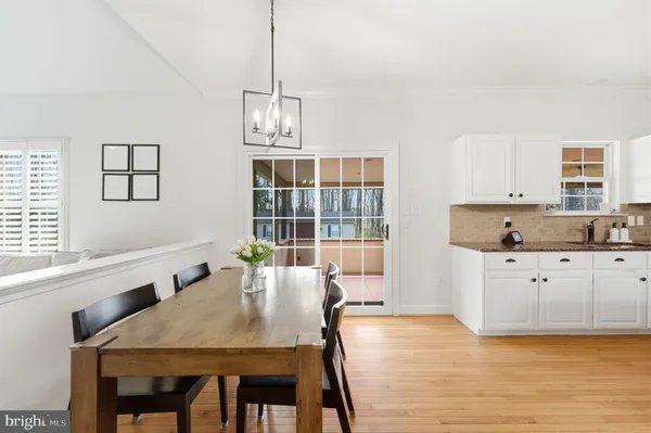 a dining room with wooden floor a chandelier a wooden table and chairs