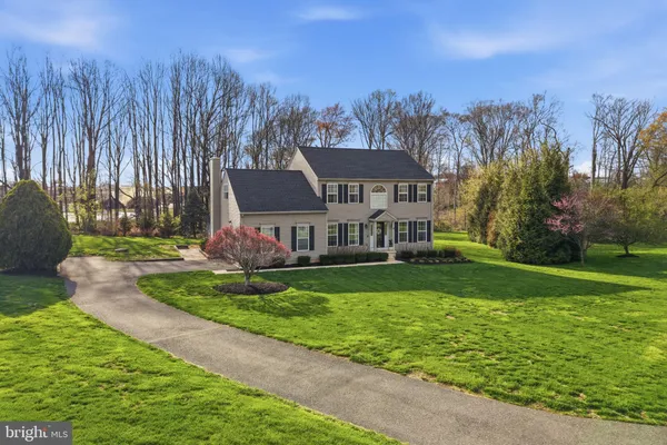 a view of a house with a big yard plants and large trees