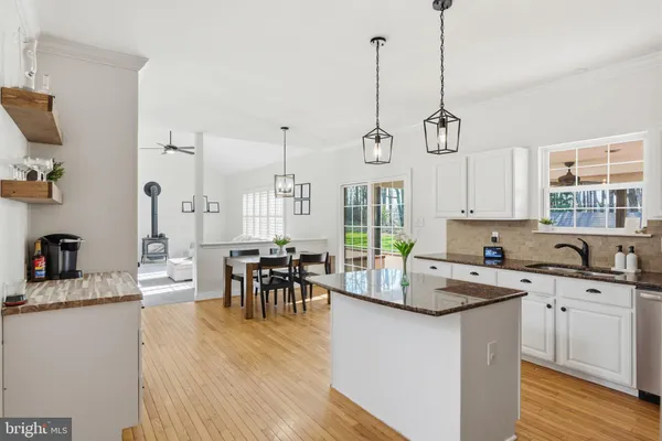 a kitchen with stainless steel appliances granite countertop a refrigerator a sink a stove and white cabinets