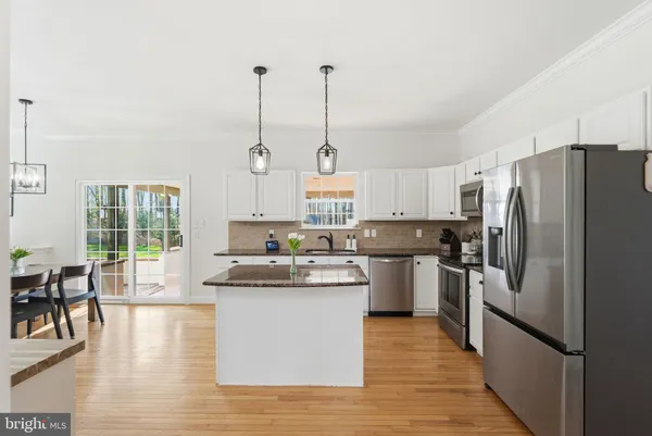 a kitchen with stainless steel appliances granite countertop a sink a stove a refrigerator and white cabinets