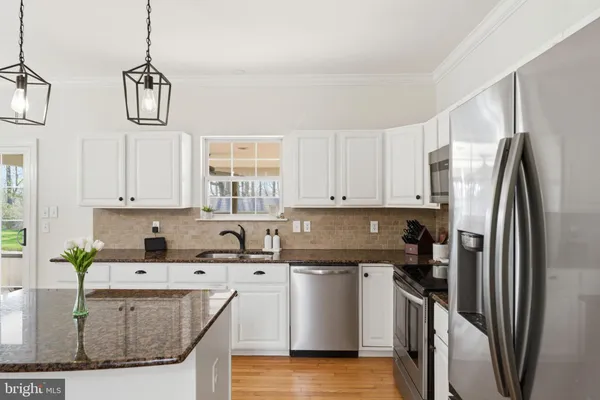 a kitchen with stainless steel appliances granite countertop a sink a stove and refrigerator