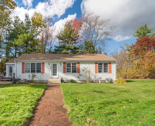 a front view of a house with a yard and trees