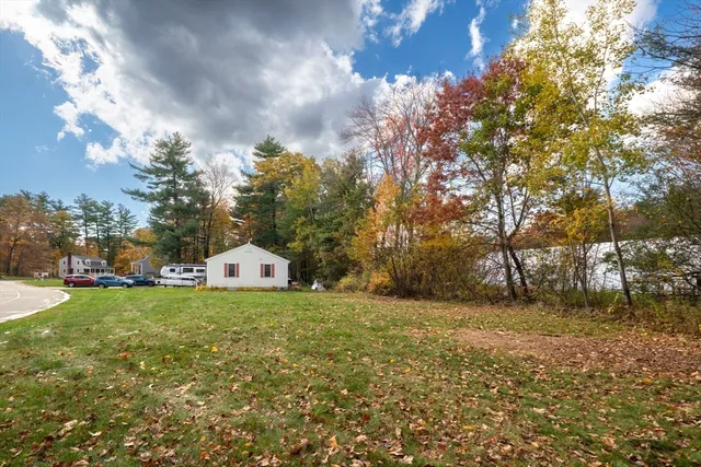 a white house with a big yard and large trees