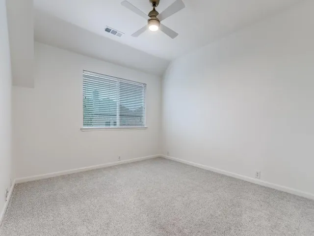 an empty room with a window and a ceiling fan
