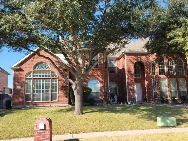 a view of a house with a large tree and a yard