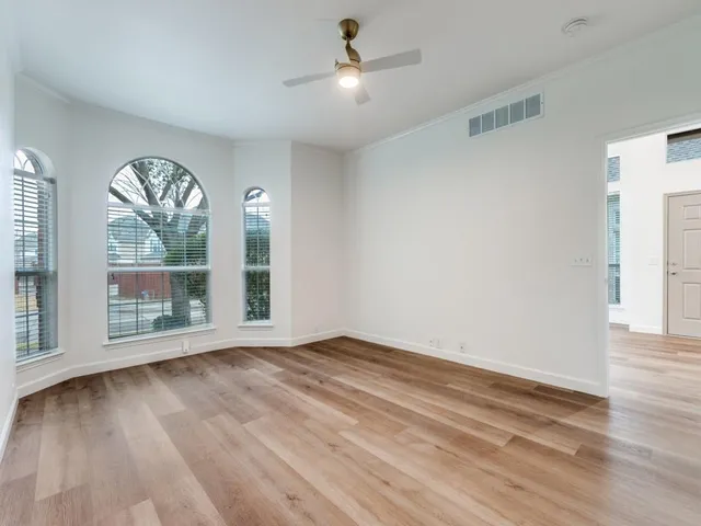 a view of an empty room with a window and wooden floor