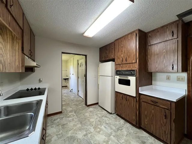 a kitchen with refrigerator cabinets and stove top oven