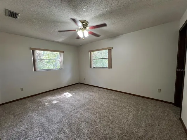 an empty room with windows and fan